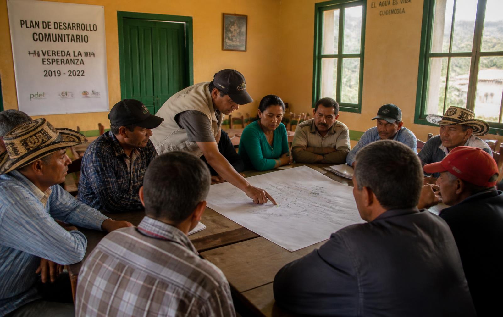 Reunión comunitaria alrededor de un mapa en un salón veredal